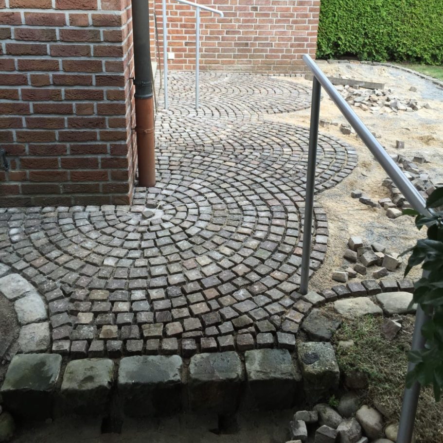 Kreisförmiges Pflastermuster mit Randsteinen an einer Hauswand Kreisförmiges Pflastermuster mit Randsteinen an einer Hauswand